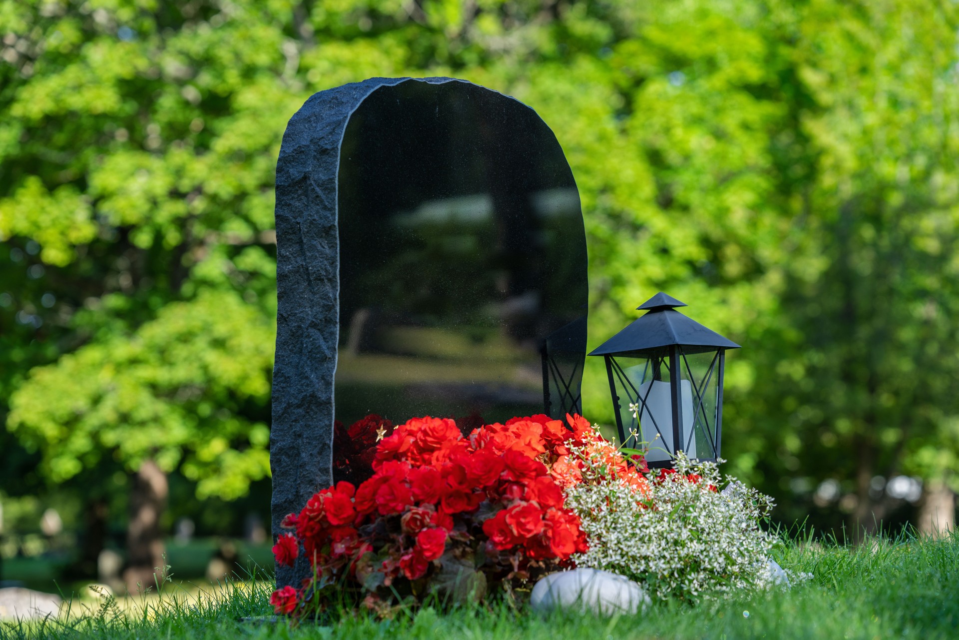 Black gravestone with red and white flowers